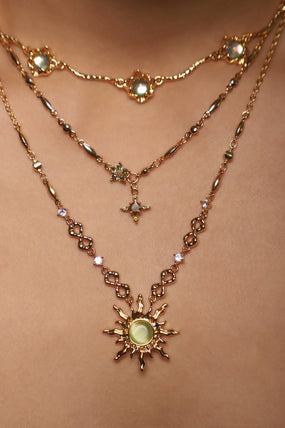 Gold-plated starlight cross necklace set with green peridot-toned gemstones, made to layer