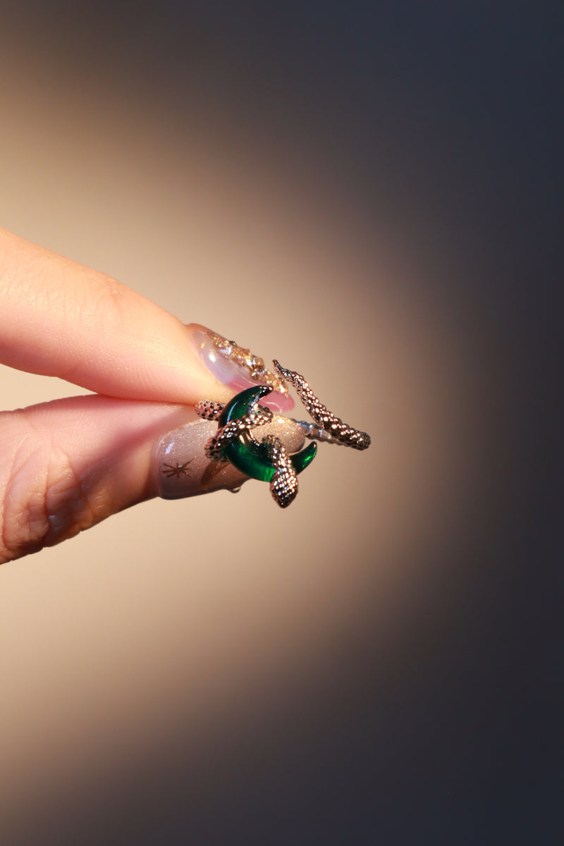 Silver-plated snake ring wrapped around a green zirconia moonstone, adjustable band