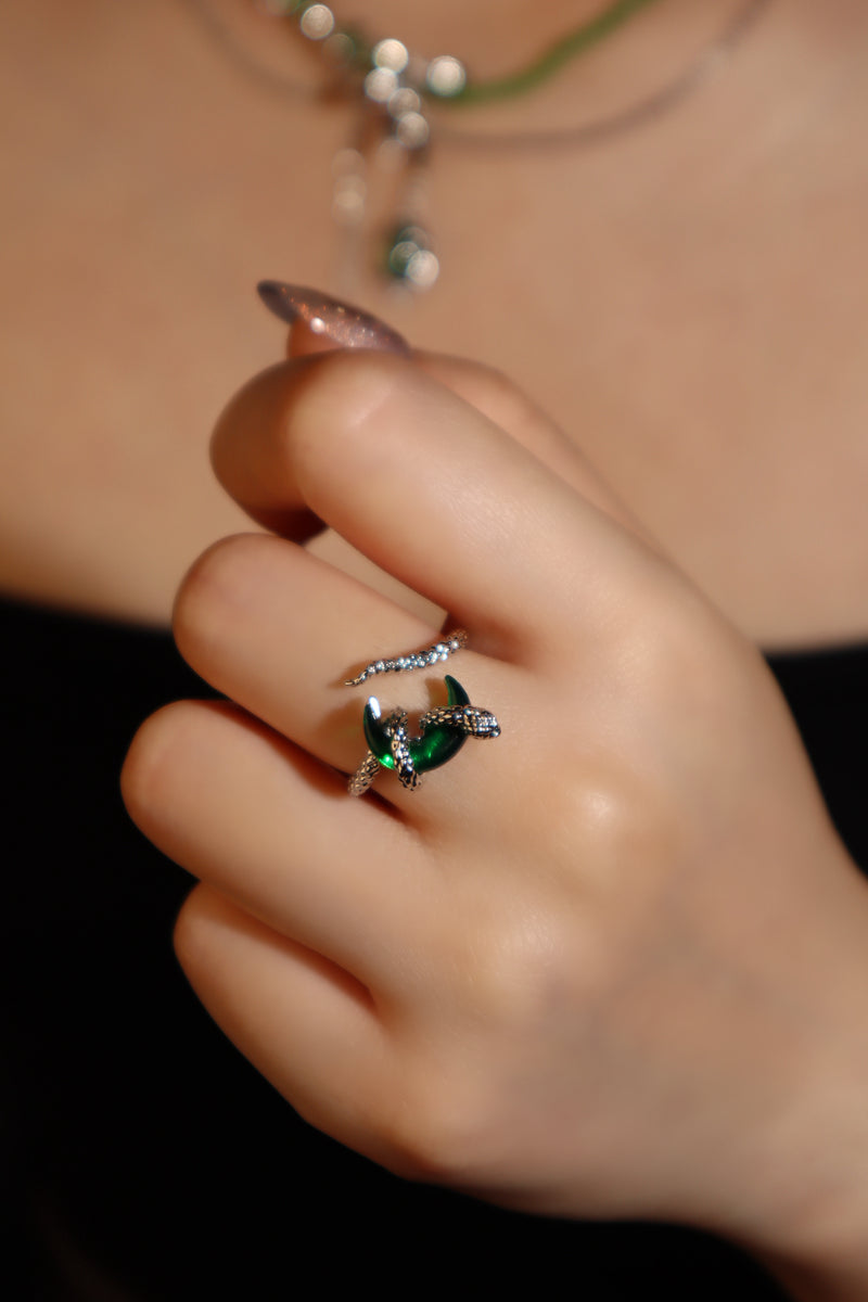 Silver-plated snake ring wrapped around a green zirconia moonstone, adjustable band