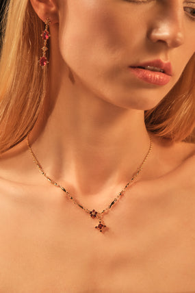 Gold-plated cross necklace with rich garnet-toned zirconia gemstones on a fine chain