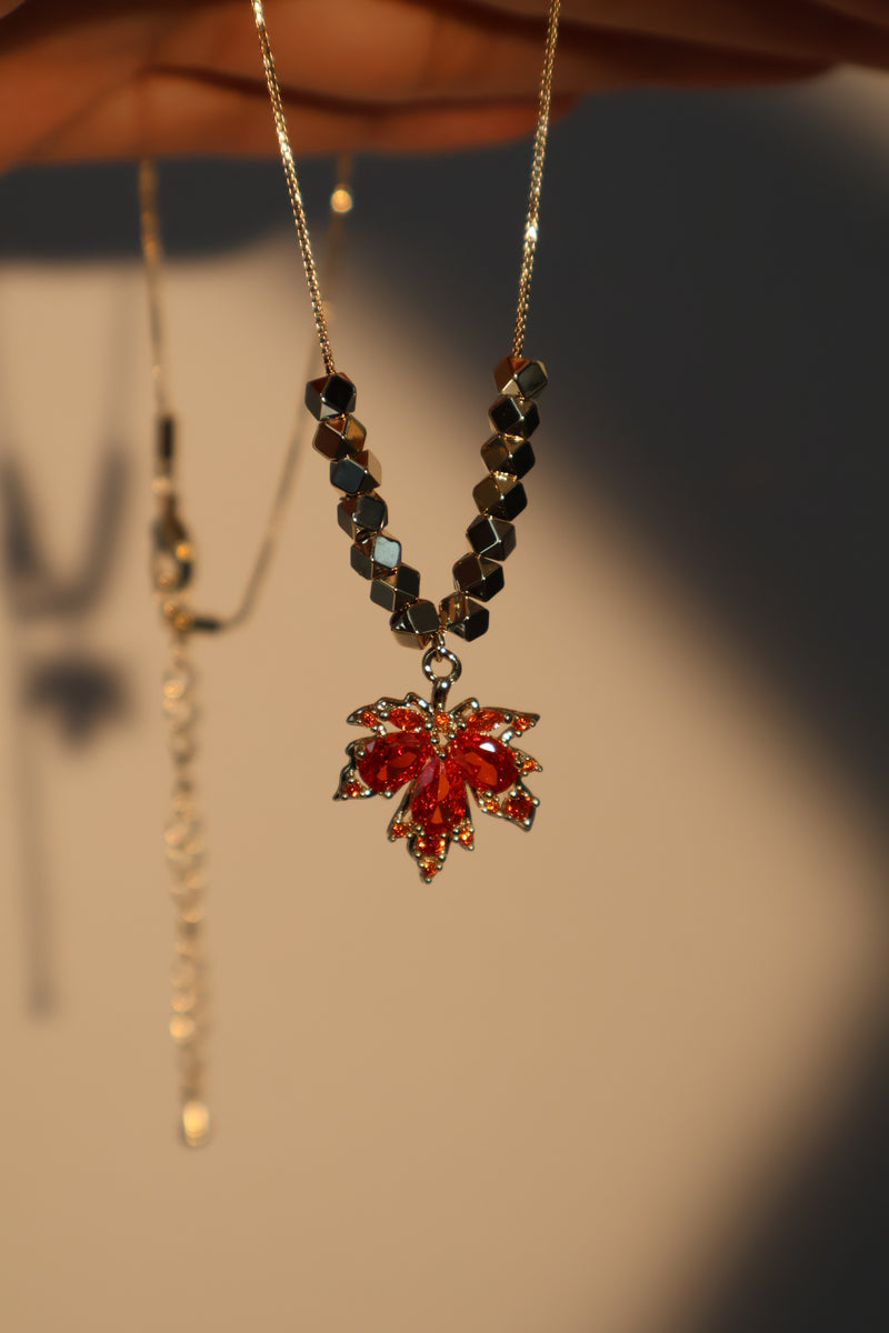 Gold-plated maple leaf pendant necklace with a red zirconia stone on a fine chain