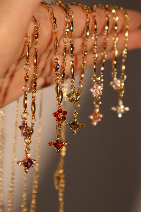 Gold-plated cross necklace with rich garnet-toned zirconia gemstones on a fine chain