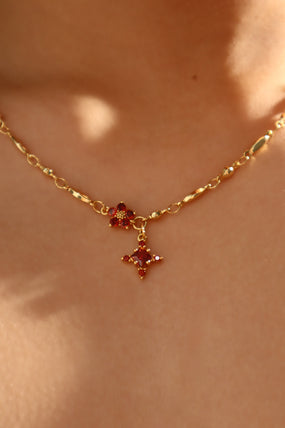 Gold-plated cross necklace with rich garnet-toned zirconia gemstones on a fine chain