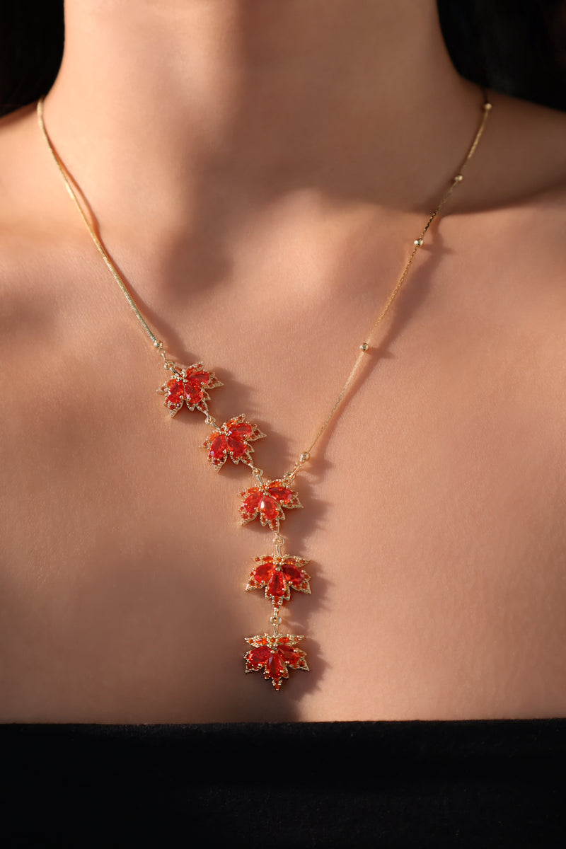 Gold-plated maple leaf necklace with red cubic zirconia gemstones on an adjustable chain