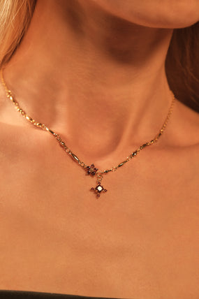 Gold-plated cross necklace with rich garnet-toned zirconia gemstones on a fine chain