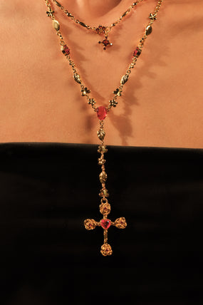 Gold-plated lariat necklace with red gemstones forming a dainty cross pendant