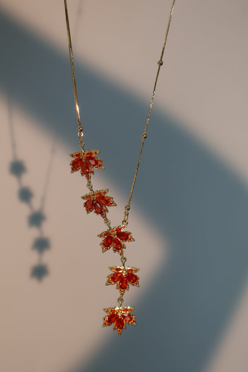 Gold-plated maple leaf necklace with red cubic zirconia gemstones on an adjustable chain
