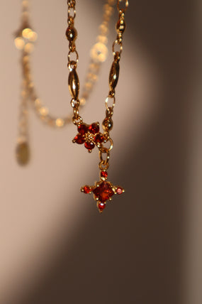 Gold-plated cross necklace with rich garnet-toned zirconia gemstones on a fine chain