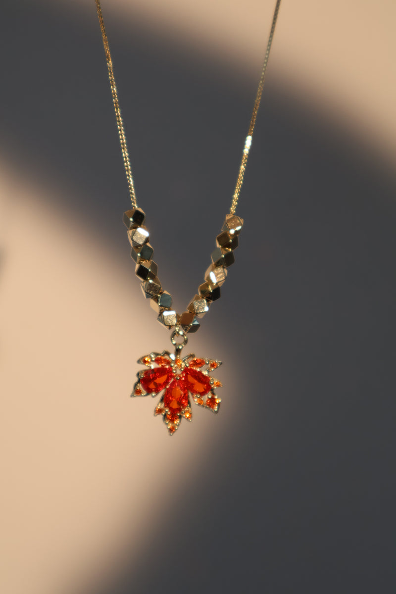 Gold-plated maple leaf pendant necklace with a red zirconia stone on a fine chain
